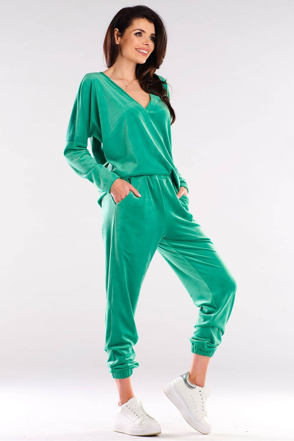 Woman modeling green v-neck leisure set with long sleeves and jogger pants, perfect for urban style. Made in Poland, polyester blend.