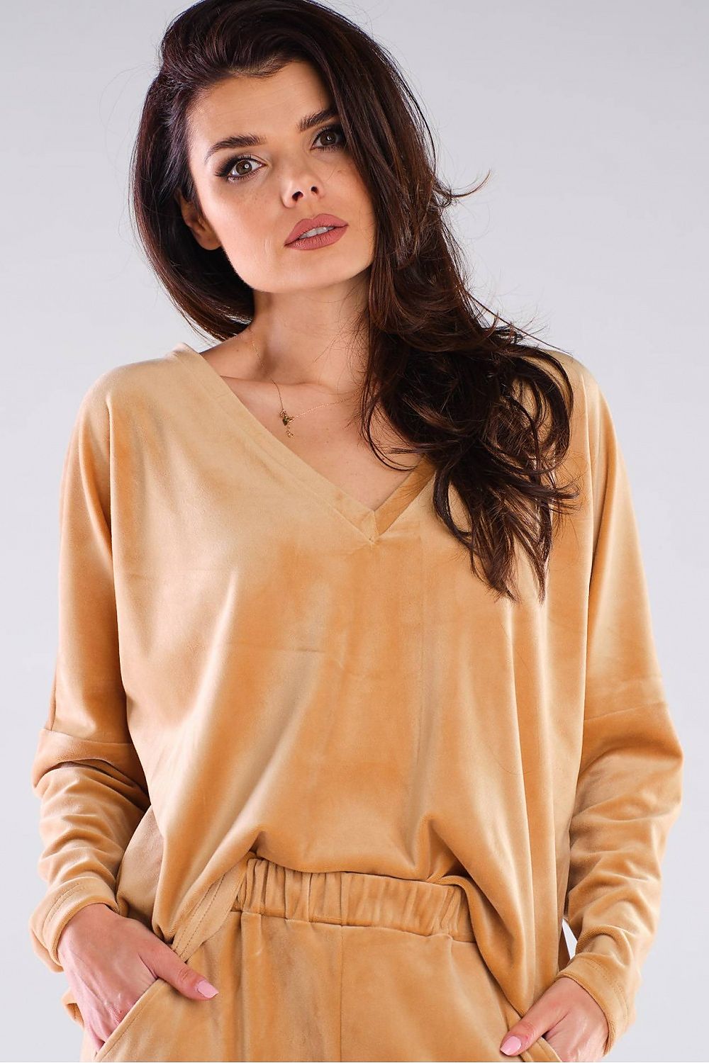 Woman wearing a stylish beige V-neck long-sleeve pullover in relaxed urban style, perfect for any body shape.