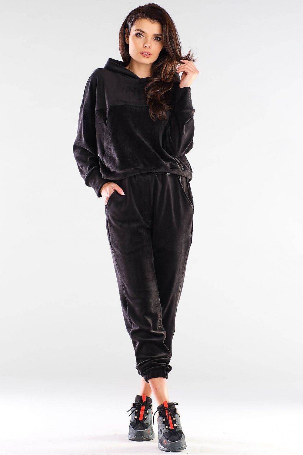 Woman wearing a black suede hoodie and joggers set, paired with sneakers. Versatile and stylish loungewear, designed in Poland.