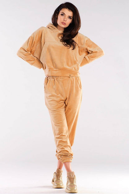 Woman wearing a beige velour hoodie and jogger set, styled with sneakers.