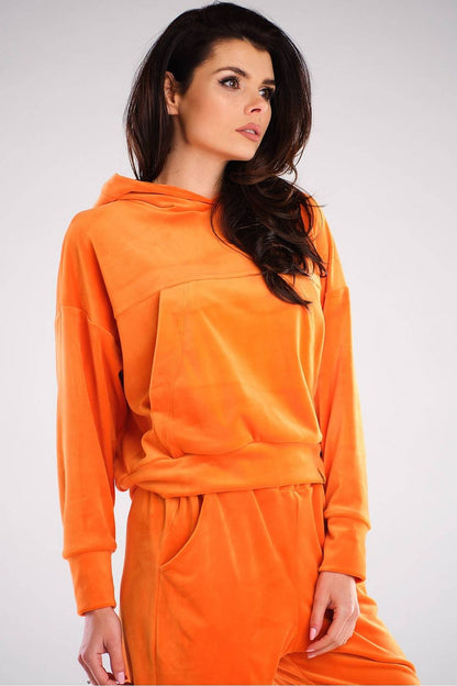 Model wearing an orange velour kangaroo pocket hoodie, designed in Poland. Casual, loose fit, perfect with jeans and sneakers.