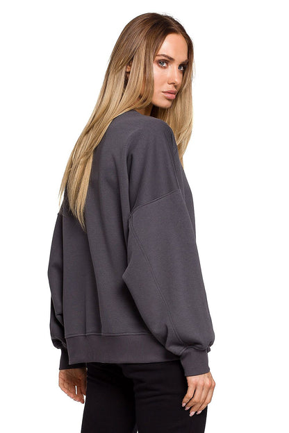 Model wearing oversized pullover with unique print by MOE, made from enzyme-enhanced cotton blend, shown in side view.