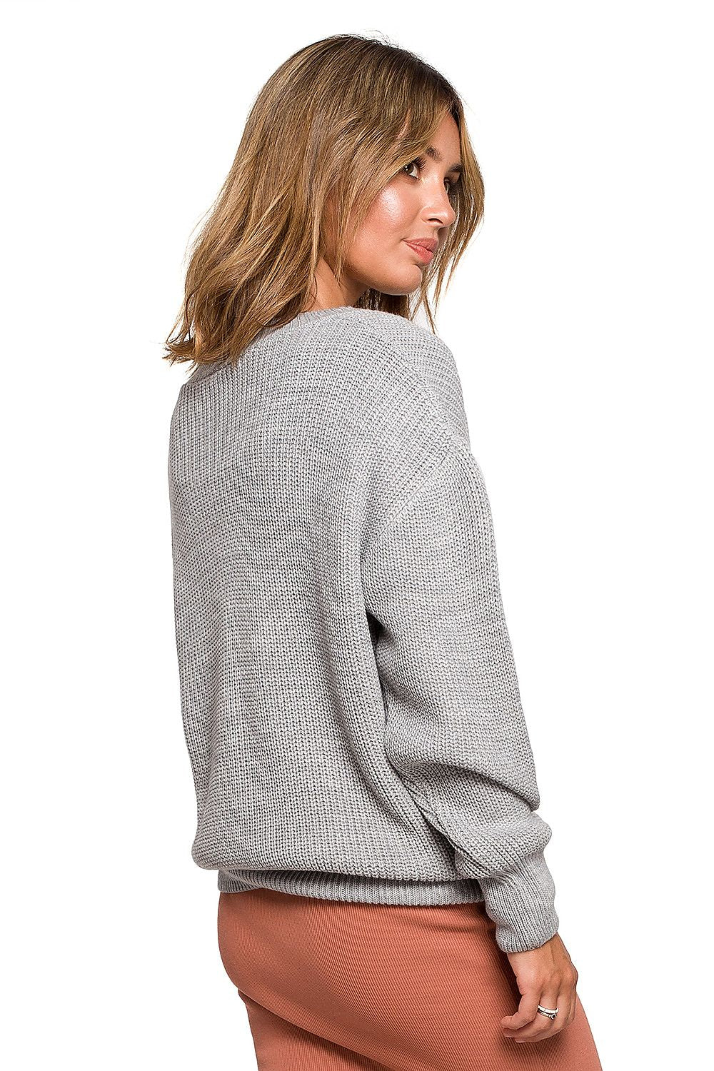 Model wearing classic grey oversized pullover with V-neck, essential for chilly autumn days, made of 100% acrylic, back view.