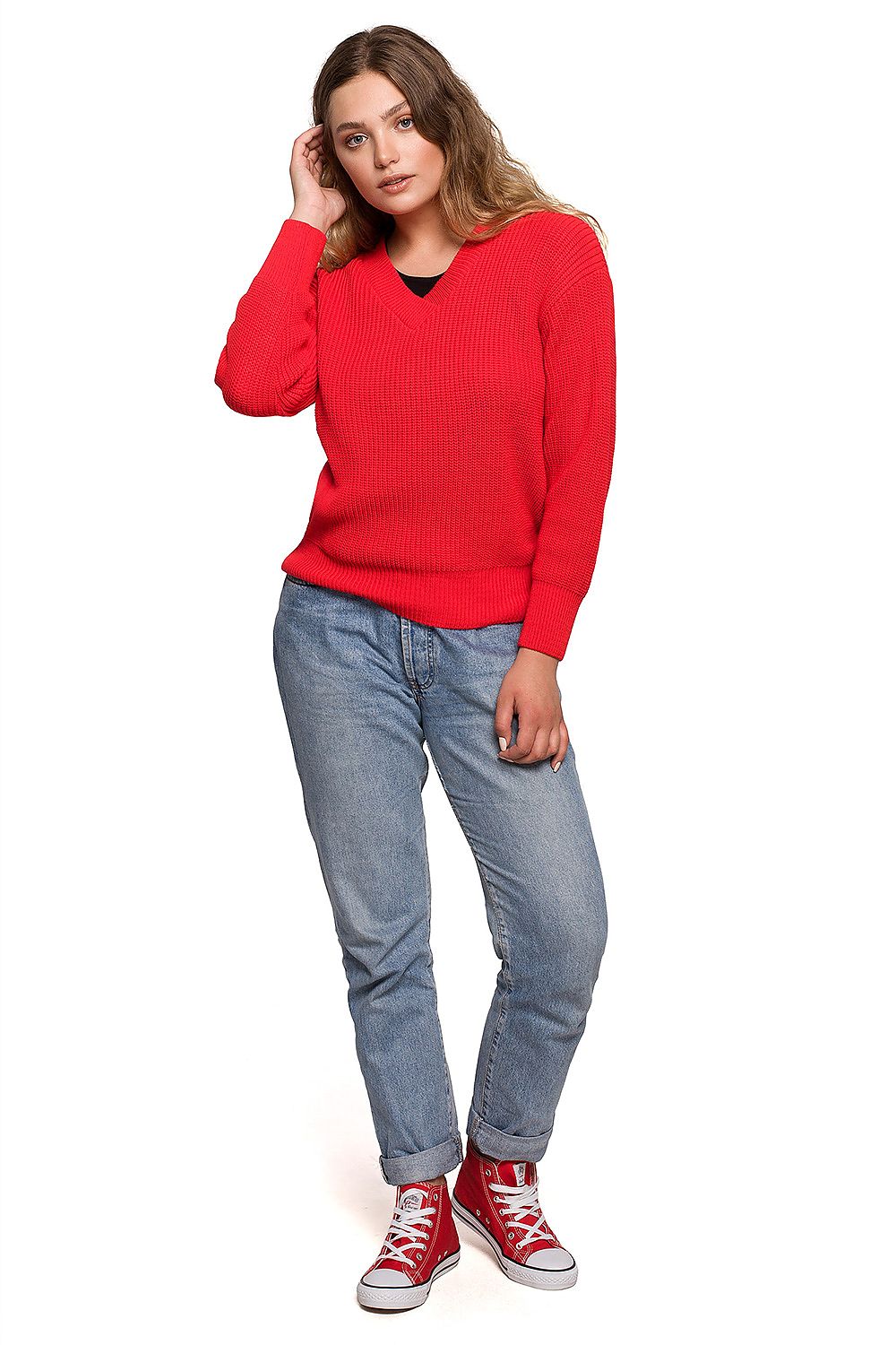 Woman wearing a red V-neck oversize pullover, paired with jeans and sneakers, perfect for staying cozy in fall weather.