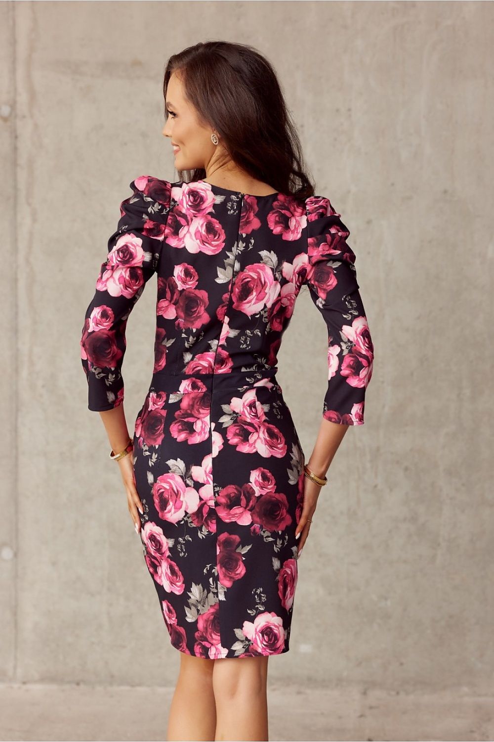 Woman wearing floral knee-length dress with puff shoulders, side view.