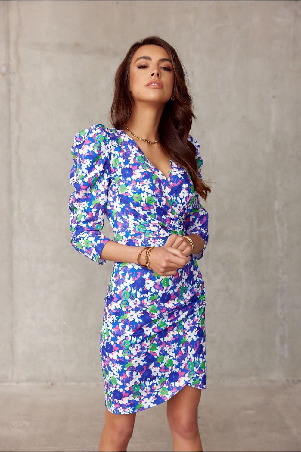 Woman in floral knee-length dress with puffed shoulders, Roco Fashion Model 176223, featuring slimming ruched design and wrap neckline.