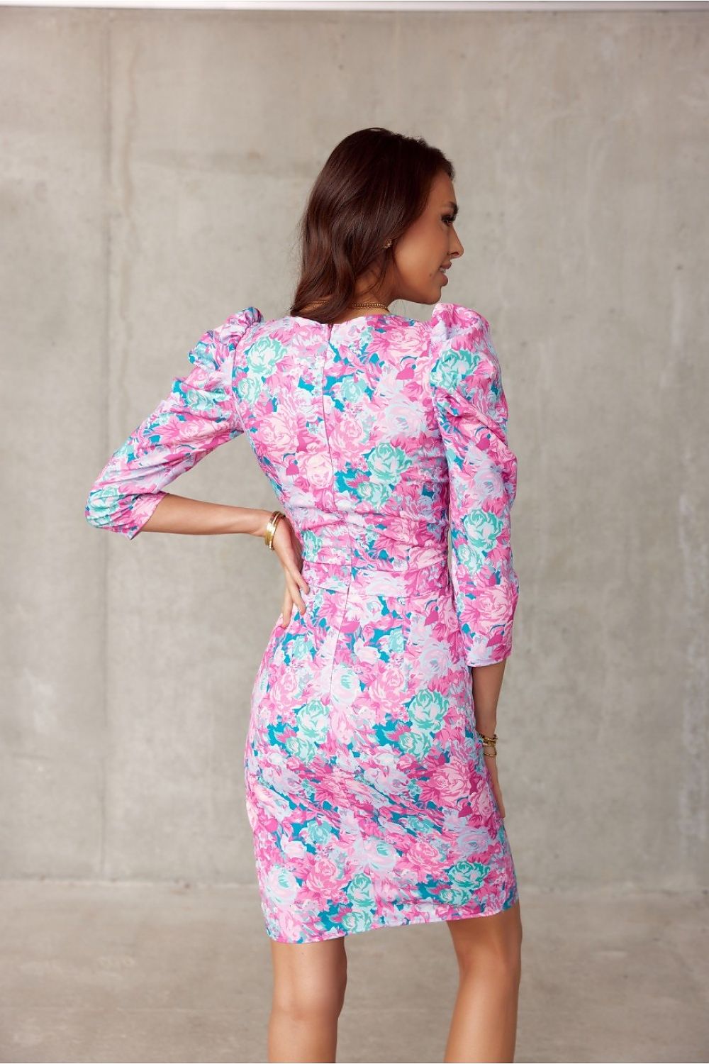 Model wearing a pink and blue floral knee-length dress with puff shoulder details and a layered neckline from Roco Fashion.