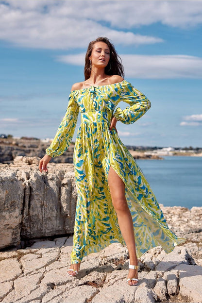 Model wearing a Roco Fashion off-shoulder floral maxi dress by the seaside.