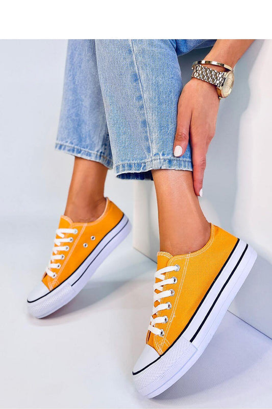 Stylish yellow high-sole sneakers worn by a person in jeans, perfect for everyday fashion.